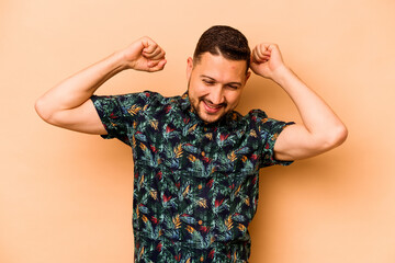 Fototapeta premium Young hispanic man isolated on beige background celebrating a special day, jumps and raise arms with energy.