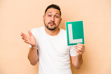 Hispanic man holding a beginner driver sign isolated on beige background