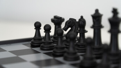 black chess pieces on a chessboard - knight and pawns close up
