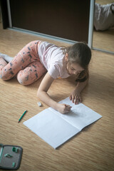 Dziecko siedzące na podłodze i rysujące na kartce
