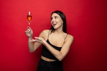 Smiling young woman with a glass of champagne on a red background