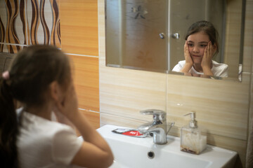 Dziewczynka myjąca twarz przed umywalką w łazience