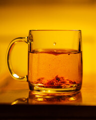 A glass mug with herbal tea on a table. Warm, tungsten light.