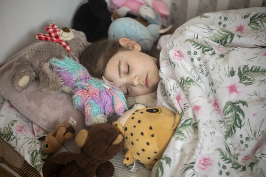 Dziecko śpiące w swoim ł&oacute;żku z misiami