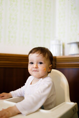 Fototapeta premium Smiling Caucasian female baby sitting in a chair and celebrating her birthday