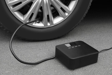 Inflating car tire with portable air pump outdoors