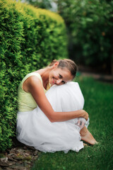 Cute girl woman in dress next to thuja hedge, beautiful classic garden and lawn