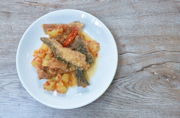 deep fried slice mango fish with pineapple and chili in sweet sour sauce on plate