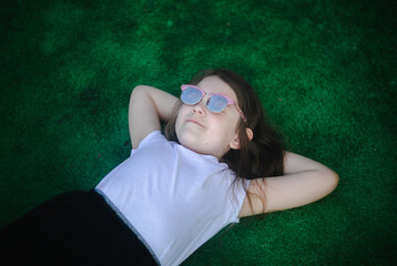 dziewczynka leży na trawie i patrzy w niebo - obrazy, fototapety, plakaty