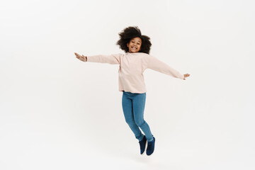 Black preteen girl with curly hair jumping and laughing