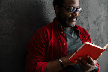 Black man writing down notes while leaning on concrete wall