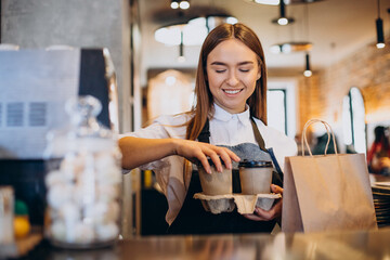 Barista woman at coffee shop preparing coffee in cardboard cups