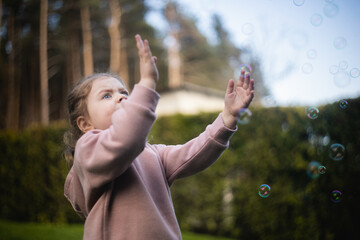 Dziewczynka bawi się bańkami na podwórku