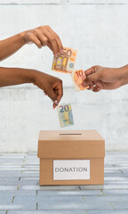charity, financial support and saving concept - close up of hands putting euro money into donation...