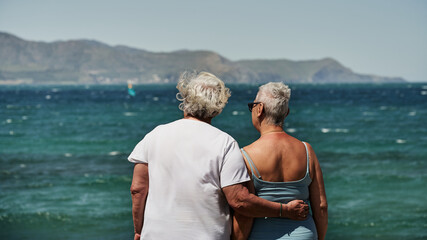 Dos mujeres contemplan el mar en la primavera al aire libre en la naturaleza con amistad 