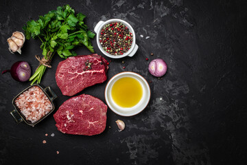 Raw beef fillet steaks with herbs and spices on a dark background. Restaurant menu, dieting, cookbook recipe top view