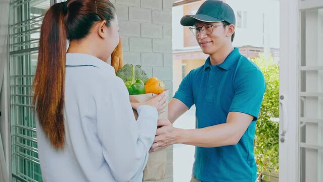Food Delivery concept. Asian delivery man hand giving bag of food, fruit, vegetable delivery to costomer grocery delivery service.