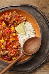 Plate of rice with chili con carne on wooden table, top view