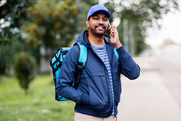 food shipping, profession and people concept - happy smiling indian delivery man with thermal...