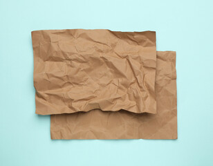 Sheets of crumpled brown paper on light blue background, top view