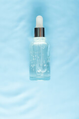 Serum glass bottle on water with drops Concept of moisturizing cosmetics with natural marine collagen. Skin care, anti-aging