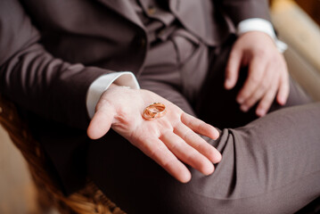 The groom holds wedding rings in his hand. Close-up view
