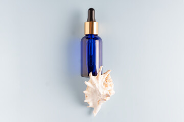 Serum bottle with pipette on blue background. Top view, flat lay. Dermatology science cosmetic...