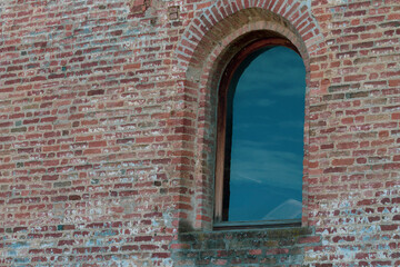 Low angle view of an old stone window reflcting sky and clouds. Copy space.