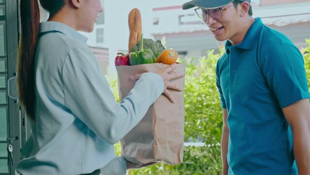 Food Delivery concept. Asian delivery man hand giving bag of food, fruit, vegetable delivery to costomer grocery delivery service.