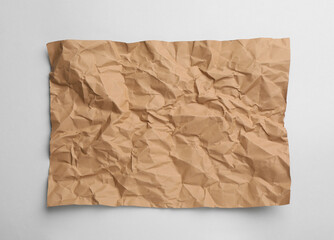 Sheet of crumpled brown paper on white background, top view