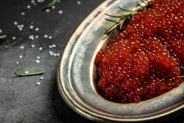 Delicious red caviar in black bowl on a concrete background. banner, menu, recipe. selective focus, place for text