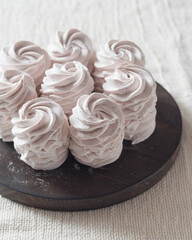 Homemade russian marshmallow - zephyr on brown wooden plate on a light table, selective focus