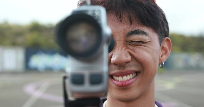 Young asian man using vintage old video camera outdoor 