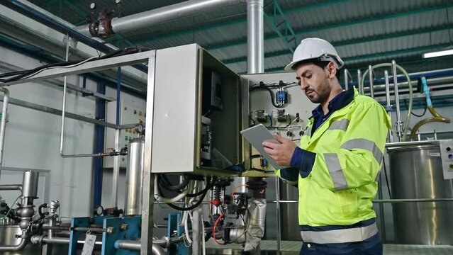 Technical engineer with laptop checking condition of transformer power control panel for observe abnormal operating status in the beverage production plant