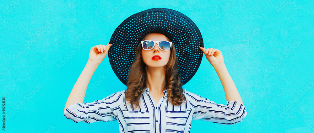 Wall mural portrait of beautiful woman model wearing black round summer hat, white striped shirt on blue backgr