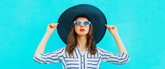 Portrait of beautiful woman model wearing black round summer hat, white striped shirt on blue background - obrazy, fototapety, plakaty