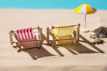 A toy beach chaise longue, seashells, a starfish on white sand with shadows. Sunlight. The concept of the sea, a beach holiday and a resort. Summer minimalism.