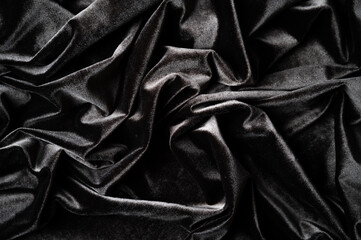 Close up view of crumpled dark velvet or silk fabric as background. Folds of brown gray silky fabric.