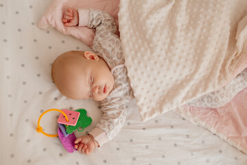 newborn baby covered with a blanket sleeps in his crib with his favorite toy. happy carefree infancy