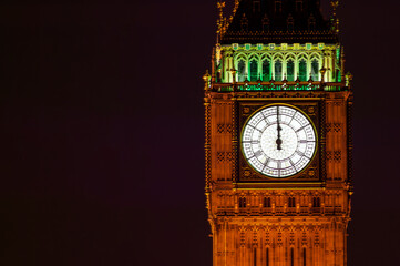 Big Ben of the Houses of Parliament London England UK at night striking midnight on new year's eve on Westminster Bridge which is a popular city landmark, stock photo with copy space - obrazy, fototapety, plakaty