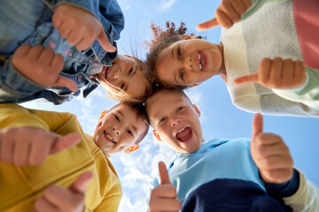 childhood, leisure and people concept - multiethnic group of happy kids showing thumbs up outdoors