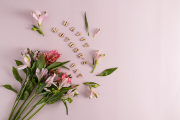 a festive composition for Mother's Day from beautiful spring flowers and inscriptions in wooden letters. pink background. top view.