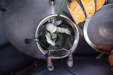 Top view male worker climb down rope access rescue the stairs into the tank stainless chemical area...