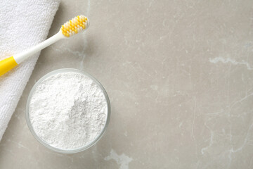 Tooth powder, brush and towel on light grey marble table, flat lay. Space for text