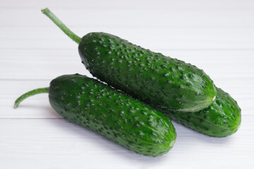 Three fresh cucumbers on light wooden boards