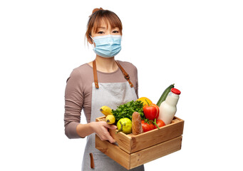 cooking, health and safety concept - happy smiling female chef in medical mask and apron with food in wooden box over white background