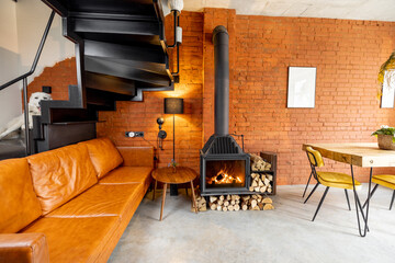 Cozy living room interior made in natural materials in loft style with burning fireplace and brick wall