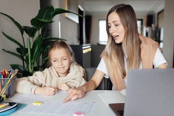 Caucasian family working and studying online at home and using laptop. Distance or remote learning for child. Pretty stylish schoolgirl studying homework math during coronavirus covid-19 quarantine