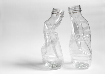 Side view of two crushed plastic bottles prepared for recycle on a light background. Waste sorting and plastic recycle concept