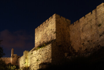 Twilight view of the landmark, stone Tower of David minaret as seen through branches and leaves of trees along the golden sunset walls of the Old City of Jerusalem. © Yehoshua Halevi